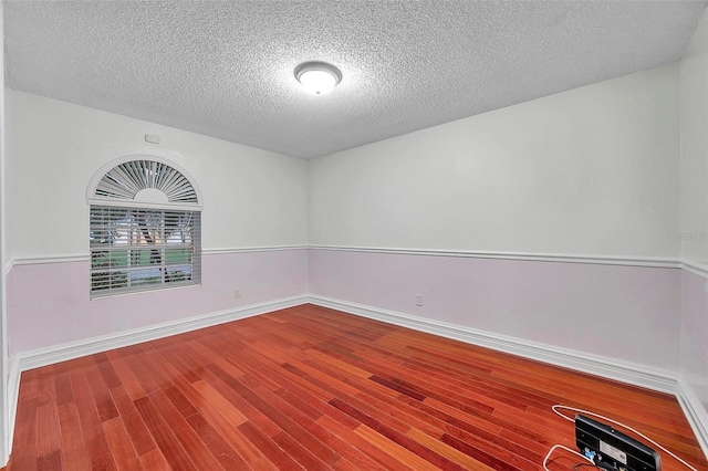 unfurnished room featuring wood-type flooring and a textured ceiling