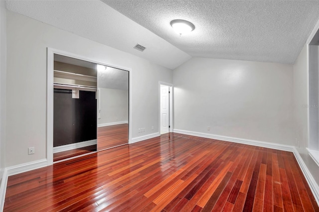 unfurnished bedroom with a textured ceiling, a closet, vaulted ceiling, and wood-type flooring