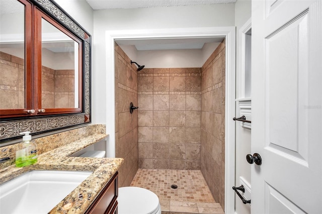 bathroom with vanity, toilet, and a tile shower