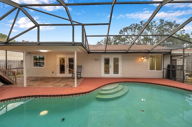 view of swimming pool featuring glass enclosure, a patio area, and french doors