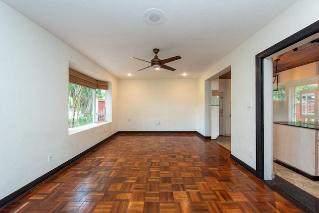 empty room featuring ceiling fan and dark parquet flooring