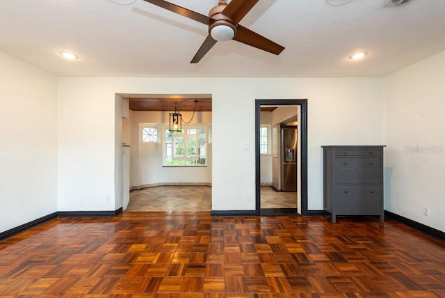 spare room with dark parquet floors and ceiling fan