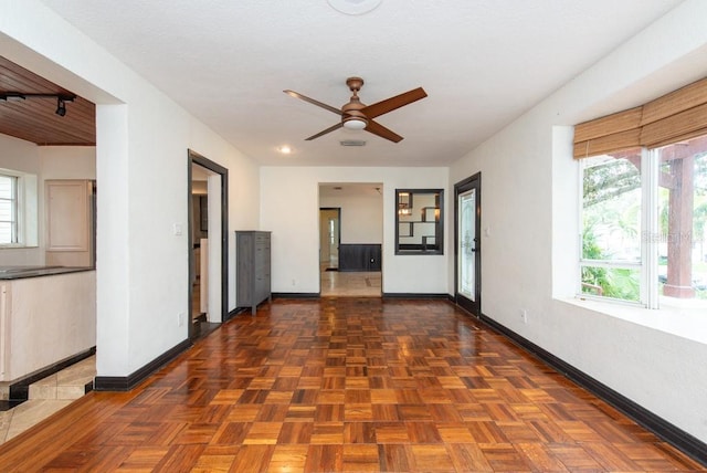 interior space featuring dark parquet flooring, ceiling fan, and a healthy amount of sunlight