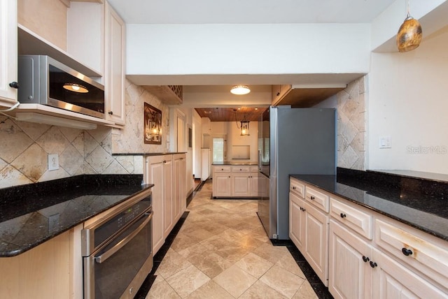 kitchen featuring dark stone counters, tasteful backsplash, pendant lighting, and stainless steel appliances