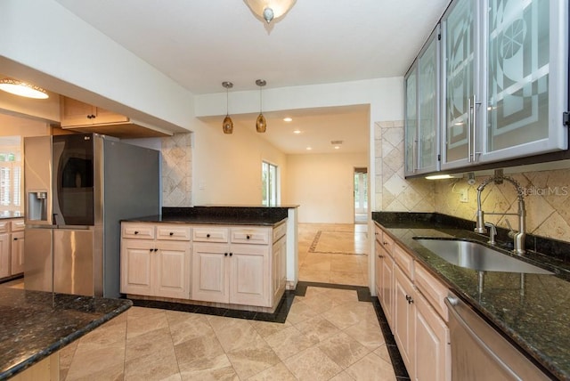 kitchen featuring stainless steel appliances, sink, dark stone counters, decorative light fixtures, and decorative backsplash