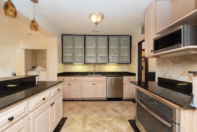 kitchen featuring hanging light fixtures, stainless steel appliances, washing machine and dryer, and tasteful backsplash