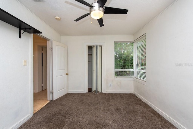 unfurnished bedroom with dark carpet and ceiling fan