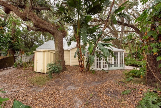 view of side of property with a sunroom and a storage unit