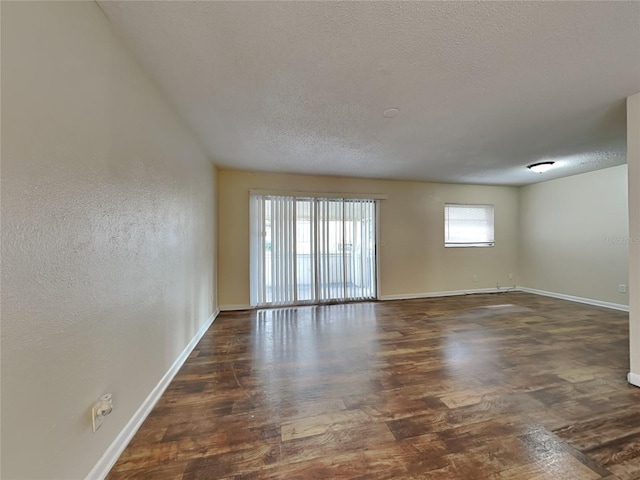 empty room with dark wood-type flooring and a textured ceiling