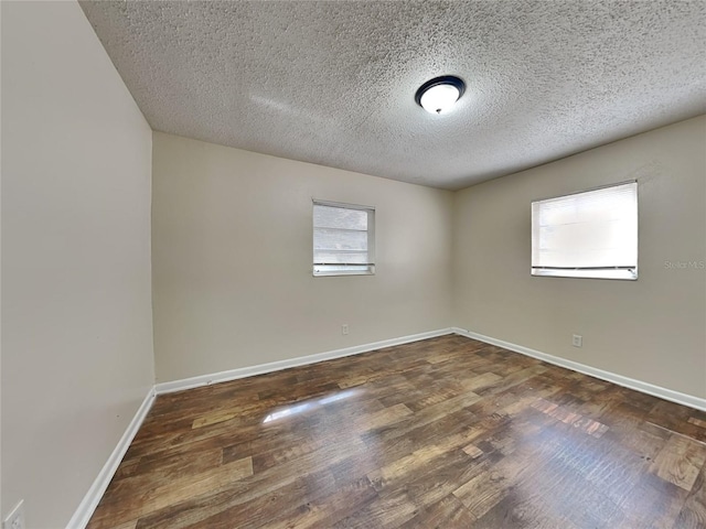 empty room with plenty of natural light, a textured ceiling, and dark hardwood / wood-style flooring