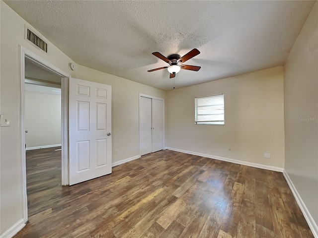 unfurnished bedroom featuring ceiling fan, dark hardwood / wood-style floors, and a textured ceiling