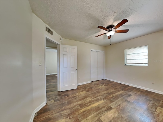 unfurnished bedroom with dark wood-type flooring, a closet, a textured ceiling, and ceiling fan