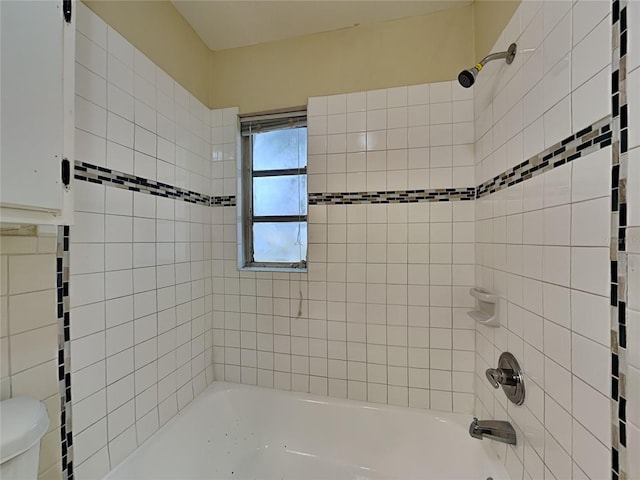 bathroom featuring toilet and tiled shower / bath