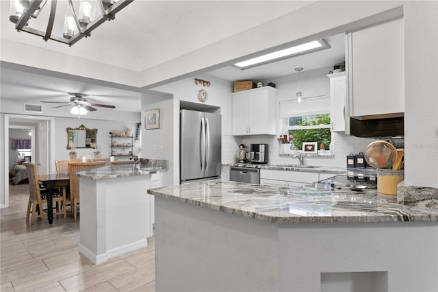 kitchen featuring stainless steel appliances, kitchen peninsula, and hanging light fixtures