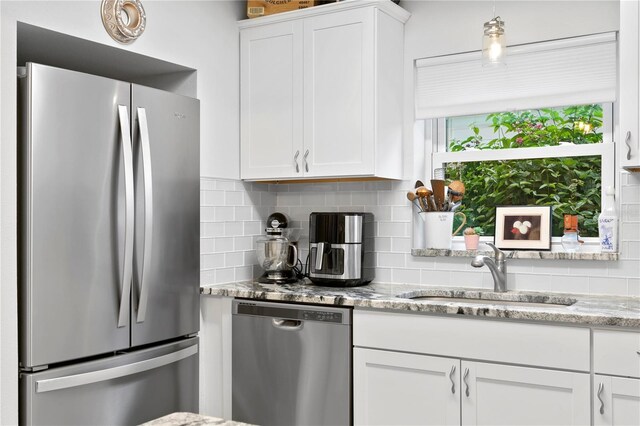 kitchen featuring sink, white cabinetry, appliances with stainless steel finishes, light stone countertops, and backsplash