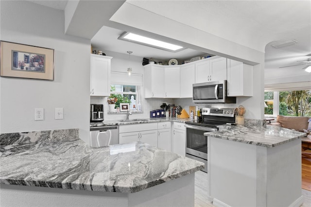 kitchen with white cabinetry, decorative backsplash, kitchen peninsula, and appliances with stainless steel finishes