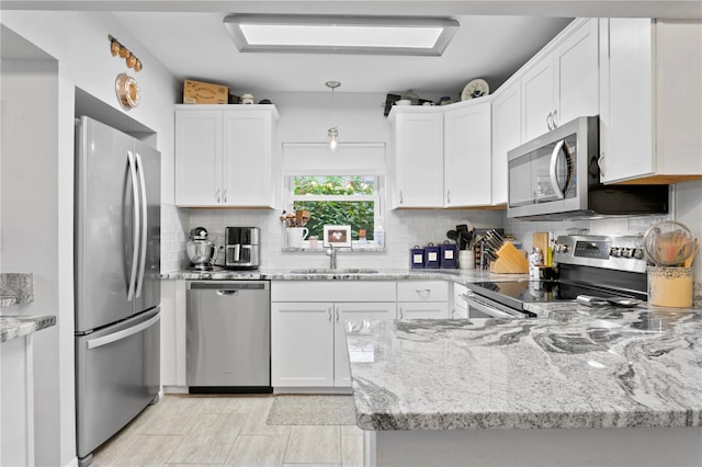 kitchen with pendant lighting, sink, appliances with stainless steel finishes, white cabinetry, and light stone counters