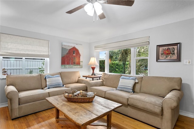 living area with wood finished floors, a ceiling fan, and baseboards