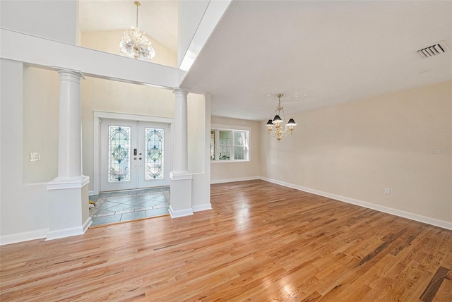 foyer entrance with a notable chandelier, light wood-type flooring, high vaulted ceiling, and french doors