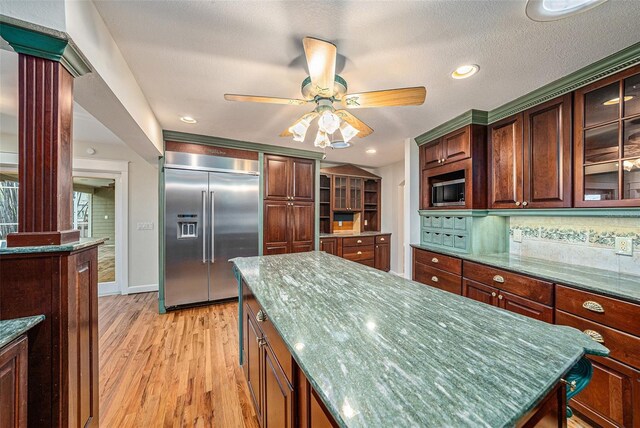 kitchen featuring tasteful backsplash, ornate columns, ceiling fan, built in appliances, and light hardwood / wood-style floors