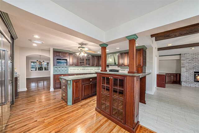 kitchen featuring premium range hood, ceiling fan, a kitchen island, and light wood-type flooring