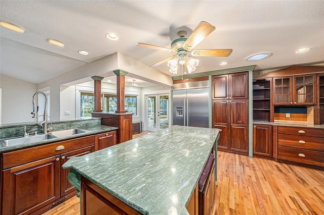 kitchen featuring a textured ceiling, sink, a kitchen island, and stainless steel built in refrigerator