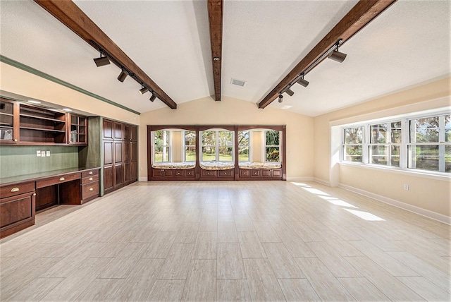 unfurnished living room featuring track lighting, light hardwood / wood-style flooring, vaulted ceiling with beams, built in desk, and a textured ceiling