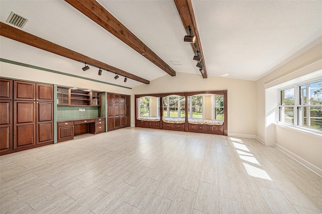 unfurnished living room with light wood-type flooring, a textured ceiling, vaulted ceiling with beams, and rail lighting