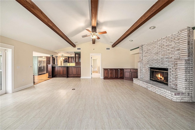 unfurnished living room featuring lofted ceiling with beams, light hardwood / wood-style floors, a fireplace, and ceiling fan