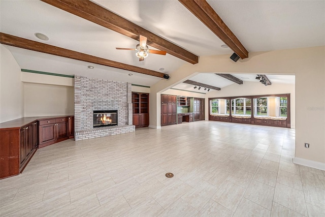 unfurnished living room with vaulted ceiling with beams, ceiling fan, and a brick fireplace