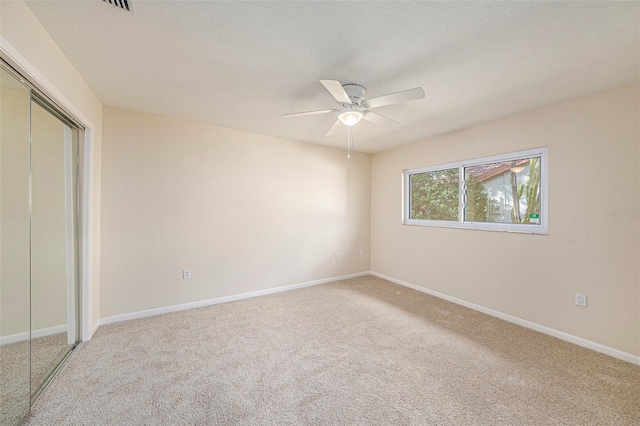 unfurnished bedroom featuring carpet flooring, ceiling fan, a textured ceiling, and a closet