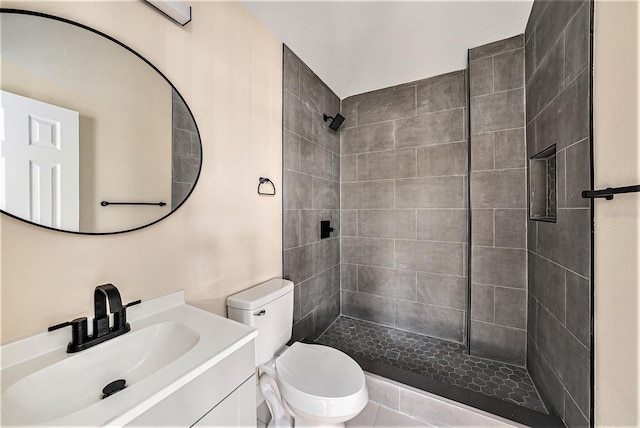 bathroom with tiled shower, vanity, and toilet