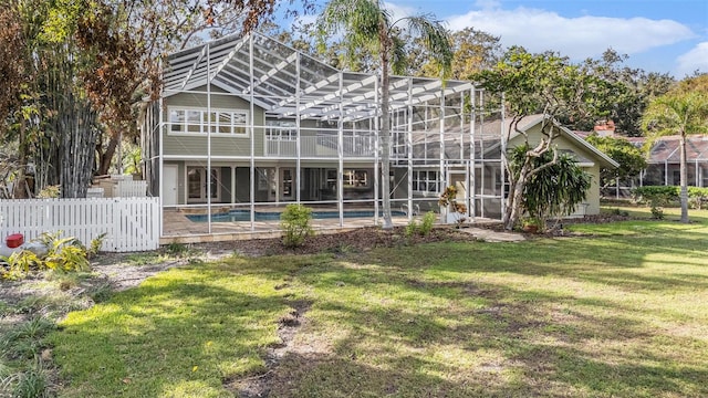 back of property with a lanai and a lawn