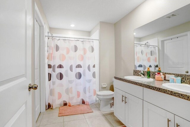 bathroom with toilet, vanity, tile patterned floors, and walk in shower