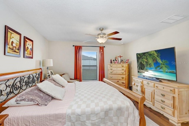 bedroom with a textured ceiling, hardwood / wood-style floors, and ceiling fan