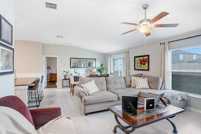 tiled living room with ceiling fan, plenty of natural light, and lofted ceiling