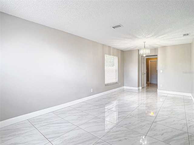 empty room with a textured ceiling and an inviting chandelier