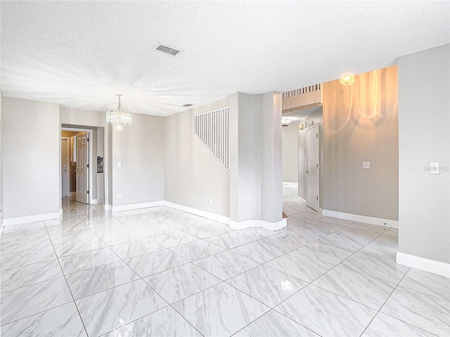 empty room featuring an inviting chandelier and a textured ceiling