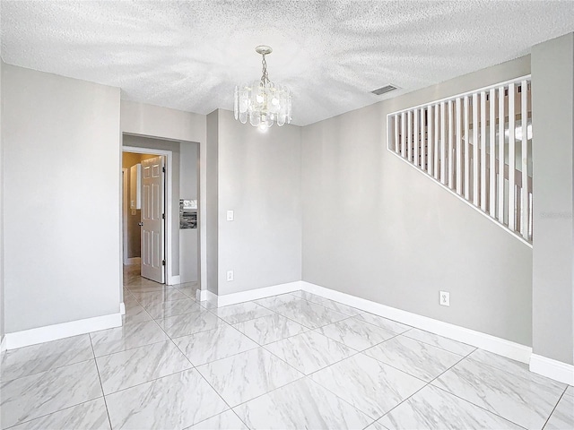 empty room with a textured ceiling and a chandelier