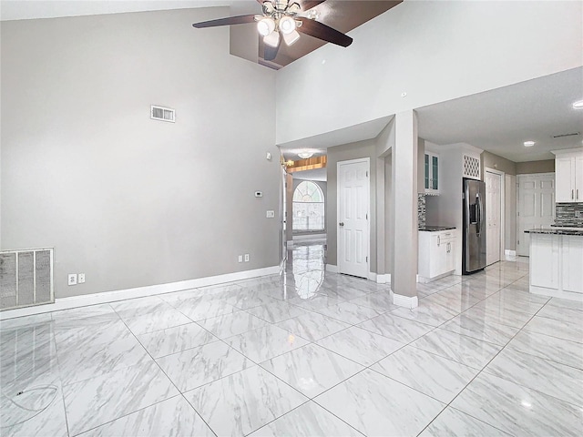 unfurnished living room with high vaulted ceiling and ceiling fan