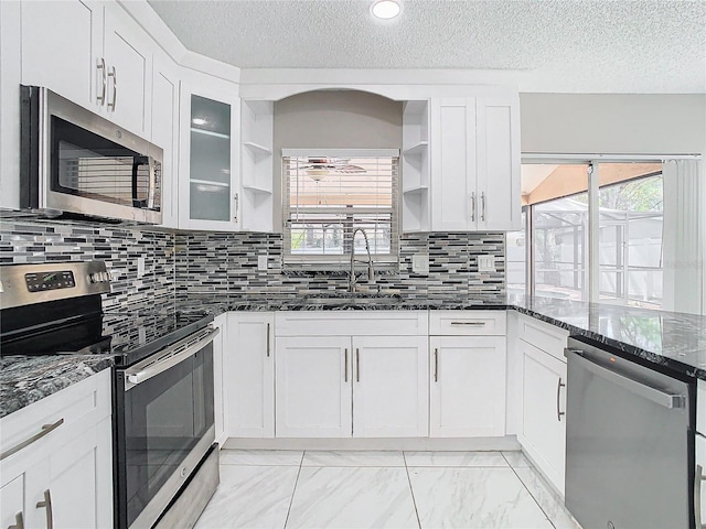 kitchen featuring dark stone countertops, white cabinetry, sink, and stainless steel appliances