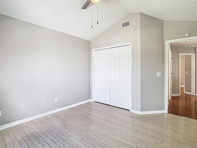 unfurnished bedroom featuring light hardwood / wood-style floors, ceiling fan, a textured ceiling, high vaulted ceiling, and a closet