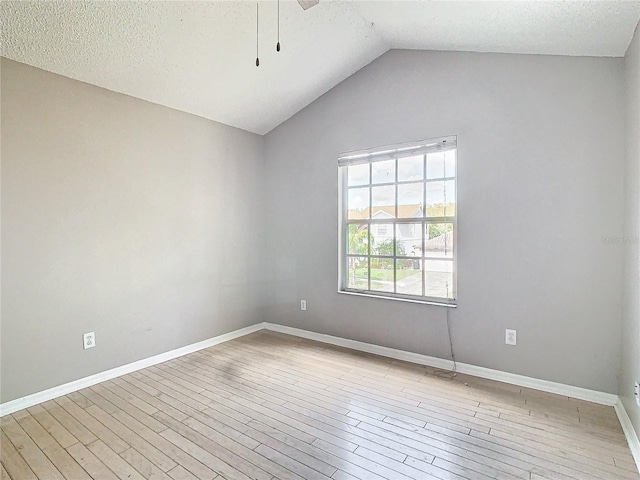 unfurnished room featuring a textured ceiling, light wood-type flooring, and vaulted ceiling