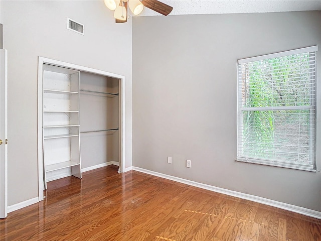 unfurnished bedroom featuring a closet, wood-type flooring, a textured ceiling, lofted ceiling, and ceiling fan