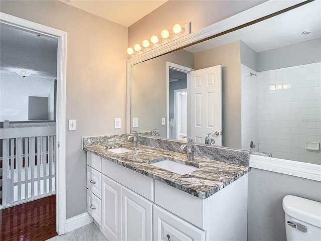 bathroom featuring toilet, vanity, hardwood / wood-style flooring, and tiled shower