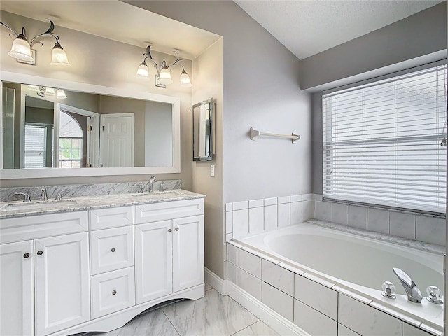 bathroom featuring lofted ceiling, vanity, and a relaxing tiled tub