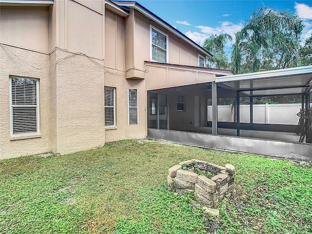 back of house featuring an outdoor fire pit, a sunroom, and a yard