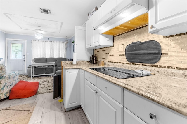 kitchen with ornamental molding, ventilation hood, white cabinets, black electric stovetop, and decorative backsplash