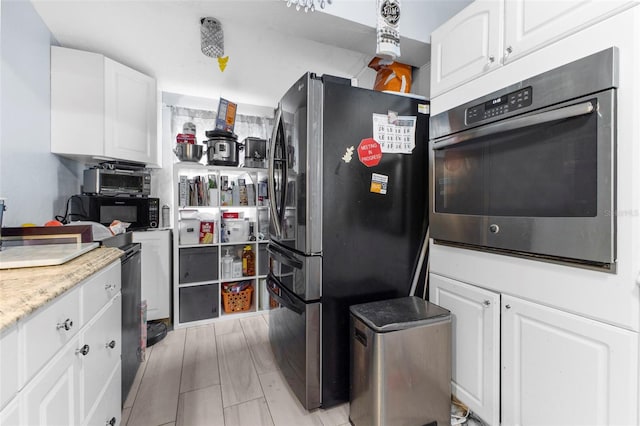 kitchen with stainless steel appliances, white cabinets, and light hardwood / wood-style flooring