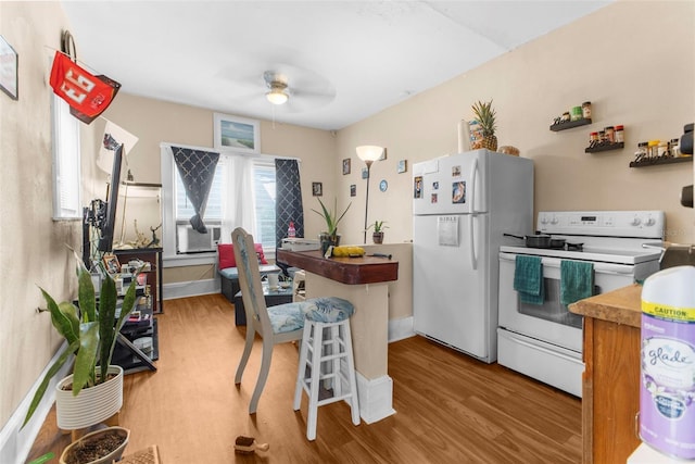 kitchen featuring light hardwood / wood-style floors, ceiling fan, white appliances, and a breakfast bar area